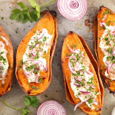 In de oven gepofte zoete bataat met room en verse kruiden