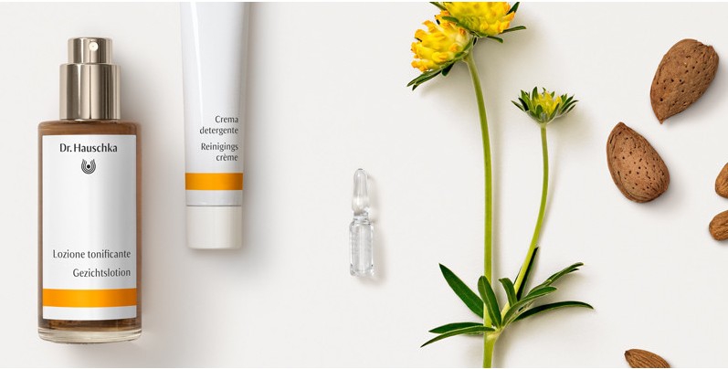 Natuurlijke Dr. Hauschka huidverzorgingsproducten zoals crème en serum, omringd door gele bloemen en amandelen, voor innerlijke en uiterlijke schoonheid